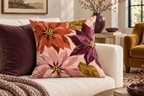 Abstract Poinsettia Christmas Printed Velvet Pillow Cover, lifestyle view 2: A prominent single pillow on a sofa beside one plain solid-colored cushion; medium interior composition, product fills at least 40 percent of frame.