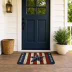 Stars and stripes patriotic doormat on a wooden front porch floor under a dark blue door.