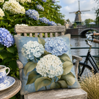 Blue hydrangea pillow cover on a wooden chair beside a Dutch canal.