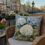 Blue hydrangea pillow cover styled on a wicker chair by a canal.