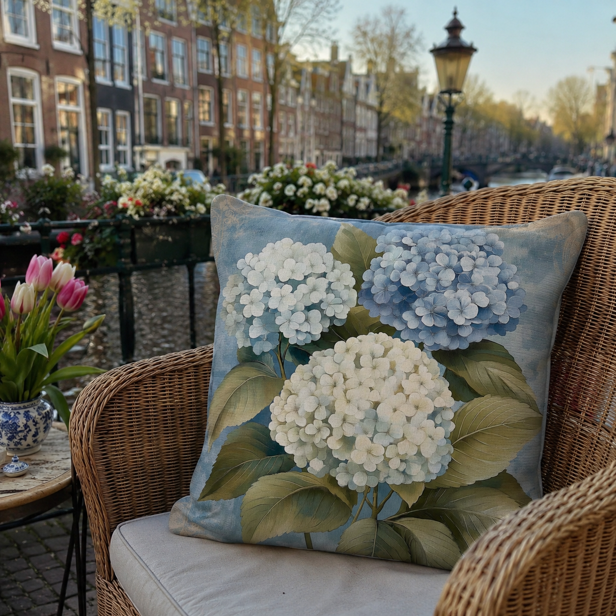 Blue hydrangea pillow cover styled on a wicker chair by a canal.