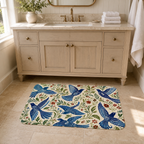 A botanical bluebird floral bath mat positioned on a bathroom floor in front of a wooden vanity.