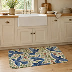 An elegant bluebird floral kitchen doormat on wooden flooring under a white farmhouse style apron sink.