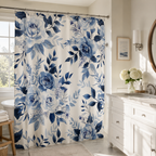 A beautiful white shower curtain with a dark blue floral rose print in a sunlit bathroom with a white vanity and large window.