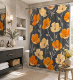 A charcoal grey shower curtain featuring vibrant orange and cream yellow poppy flowers, hanging in a bright modern bathroom with dark vanity and natural sunlight.