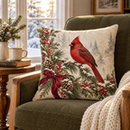 Red cardinal pillow cover on an olive armchair beside a snowy window, books and a cream knit throw.