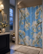 Traditional bathroom with dark navy blue cabinetry, marble countertops, and warm wall lamps, featuring a contrasting bright blue sky shower curtain.