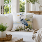 Coastal-style heron pillow cover styled on a soft neutral sofa with natural light.