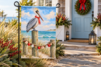 Coastal Pelican Christmas Printed Garden Flag, lifestyle view 4: One flag on its separate black garden stake in a mailbox garden with restrained October seasonal planting, wide but product-led welcoming suburban scene.