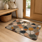 Cobblestone pattern entryway doormat placed on a light wooden floor near a front door.