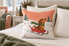 Dachshund Sleigh Christmas Printed Pillow Cover, lifestyle view 3: Centered in front of plain pillows on a neatly made guest bed; eye-level composition, believable 18-inch pillow scale.