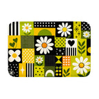 A top-down product view of a rectangular geometric doormat featuring white daisy patterns and green-yellow accents.