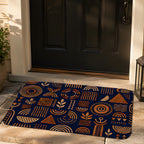 A dark navy doormat with orange geometric tribal patterns placed at the front door entryway.