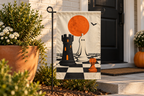 Halloween Chess Pieces Printed Garden Flag, lifestyle view 1: One flag on a simple separate black L-shaped garden stake beside a front porch planter, all of the flag readable, late-afternoon natural light.