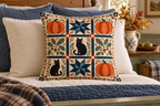 Halloween Pumpkin Patchwork Printed Pillow Cover, lifestyle view 3: Centered in front of plain pillows on a neatly made guest bed; eye-level composition, believable 18-inch pillow scale.