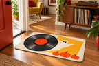 Halloween Vinyl Record Party Printed Floor Mat, lifestyle view 1: One mat laid flat INSIDE the front door, full landscape mat and all four rounded corners visible at small accent-mat scale, angled downward photography.