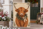 Highland Cow Christmas Printed Garden Flag, lifestyle view 3: Closer view of the flag on its separate black L-shaped stake near a porch post, the real cloth top sleeve threading over the horizontal bar, print clearly readable.