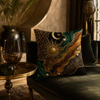 A luxury astrological sun and moon print pillow styled on a dark green upholstered chaise lounge, paired with a polished brass side table, an elegant glass chalice, and exotic home decor.
