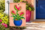 Monster Venus Flytrap Printed Garden Flag, lifestyle view 3: Closer view of the flag on its separate black L-shaped stake near a porch post, the real cloth top sleeve threading over the horizontal bar, print clearly readable.