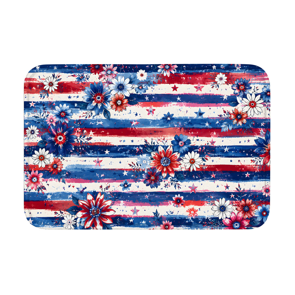 An overhead isolated product mockup of a rectangular floor mat decorated with a patriotic Americana theme, featuring red, white, and blue watercolor stripes, scattered stars, and vibrant blooming flowers.