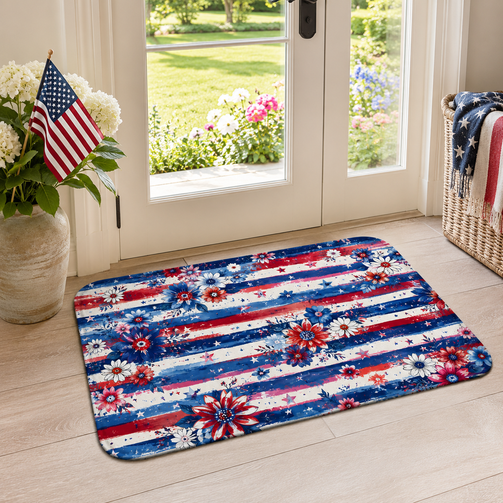 A festive 4th of July style floral floor mat accenting a glass patio door, paired with a ceramic vase holding white flowers and a small American flag.