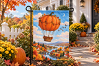 Pumpkin Hot Air Balloon Printed Garden Flag, lifestyle view 4: One flag on its separate black garden stake in a mailbox garden with restrained October seasonal planting, wide but product-led welcoming suburban scene.