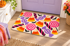 Retro Halloween Candy Printed Floor Mat, lifestyle view 1: One mat laid flat INSIDE the front door, full landscape mat and all four rounded corners visible at small accent-mat scale, angled downward photography.